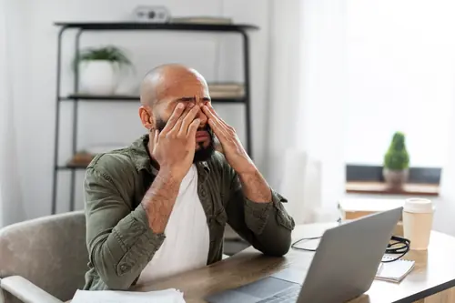 Man rubbing his eyes during prolonged screen use